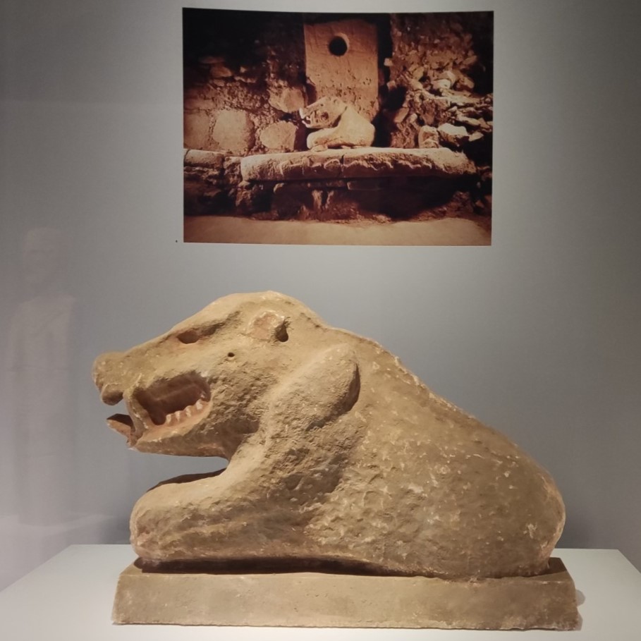 Ausstellungsstück: Skulptur eines Wildschweins, darüber ein Foto des Objekts in situ