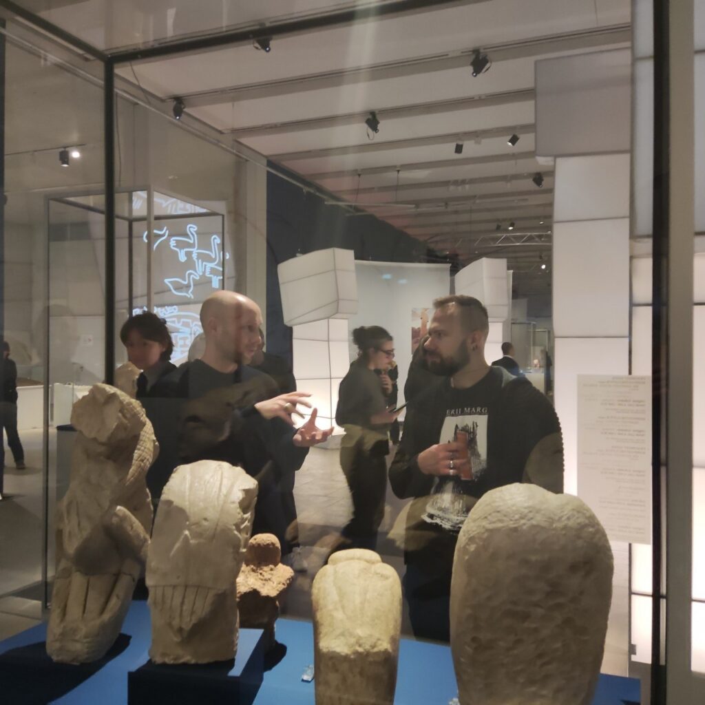 Blick durch eine Vitrine mit Ausstellungsstücken auf einige Mitglieder des WiNoDa-Teams